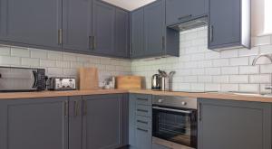 a kitchen with dark blue cabinets and appliances at Can Brow in Rusland