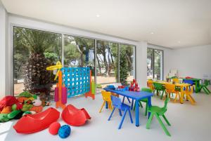 a room with a table and chairs and a play area at Hipotels Bahía Grande Aparthotel in Cala Millor