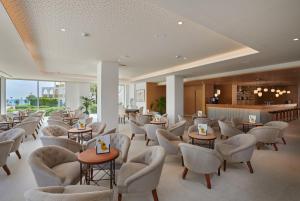 a waiting room with chairs and tables and a bar at Hipotels Bahía Grande Aparthotel in Cala Millor