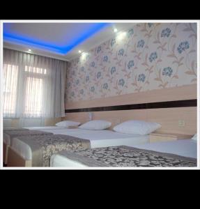 a bedroom with three beds and a wall with floral wallpaper at OTEL BURAK in Unye