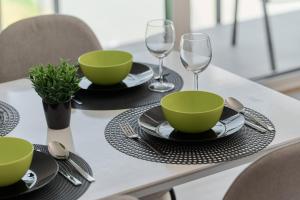 a table with green bowls and plates and wine glasses at Na Grobli Riverside Apartment & FREE GARAGE by Renters in Wrocław