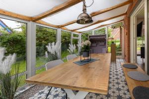 a screened dining room with a wooden table and chairs at Boutique 54° Nord in Büsum