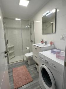 a bathroom with a shower toilet and a washing machine at Apto Sol y Mar in Maspalomas