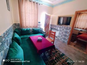 sala de estar con sofá verde y mesa en Chalets ITO Atlas Timnay, en Midelt