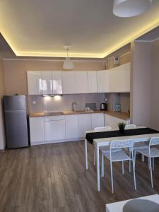 a kitchen with white cabinets and a table and chairs at Apartament Słowińców 35 in Wejherowo