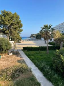 Playa d'Or 16 / Cala D'Or / Mallorca في كالا ذاور: طريق يؤدي إلى شاطئ به أشجار نخيل ومبنى