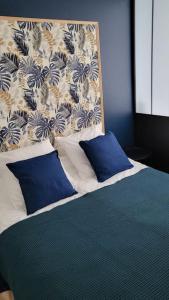 a bed with blue and white pillows in a bedroom at La Suite de Lily in Talence