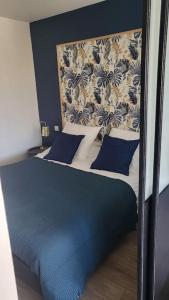 a bedroom with a blue and white bed with blue pillows at La Suite de Lily in Talence
