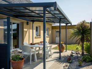 een terras met een tafel en stoelen onder een pergola bij Holiday Home Rève de Plage by Interhome in Santec