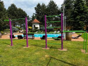 a playground with purple and green poles in the grass at Hotel Celnice in Břeclav