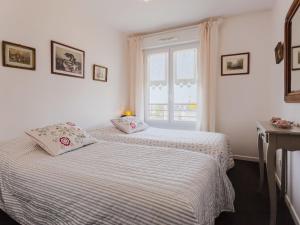 a white bedroom with two beds and a window at Apartment Elisa-1 by Interhome in Trouville-sur-Mer