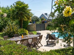Un patio con mesa y sillas y una piscina. en Holiday Home Ty Keriquel by Interhome, en Névez