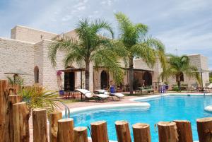 una piscina con palme e un edificio di Riad Titima Essaouira a Essaouira