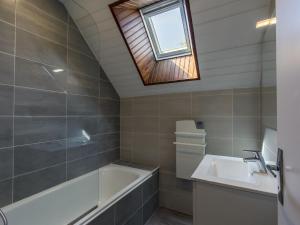 Un baño con bañera, lavabo y ventana. en Holiday Home Ty Keriquel by Interhome, en Névez