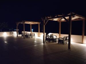 Astradeni luxury apartments Vootis في Páloi: فناء مع كراسي ومظلات في الليل
