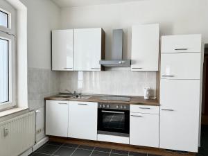 a kitchen with white cabinets and a stove at Ferienwohnung Flaming House Bitterfeld in Bitterfeld
