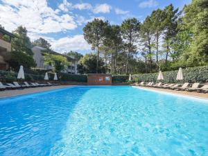 a large swimming pool with chairs and umbrellas at Apartment Village Cheval Spa Résidences-6 by Interhome in Lacanau-Océan