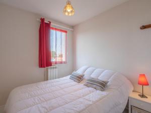 a white bed in a bedroom with a red window at Apartment Les Balcons de l'Atlantique-11 by Interhome in Pontaillac