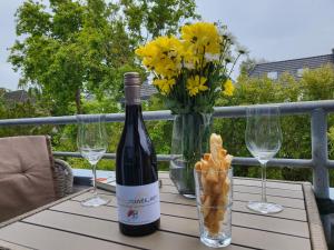 - une bouteille de vin et des verres sur une table avec des fleurs dans l'établissement Ferienwohnung "Emil", à Sankt Peter-Ording