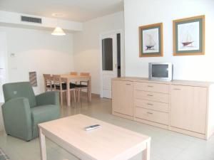 a living room with a tv and a chair and a table at Apartamentos Mestral in L'Escala