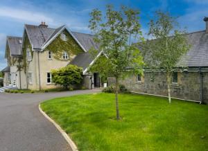 una gran casa de piedra con un árbol en el patio en Cluain Ard Holiday Home, 