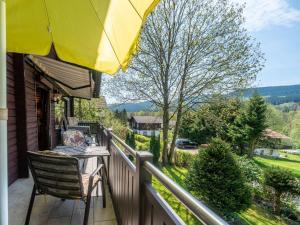 einen Balkon mit einem Tisch und einem gelben Regenschirm in der Unterkunft Apartment Am Hohen Bogen-45 by Interhome in Arrach