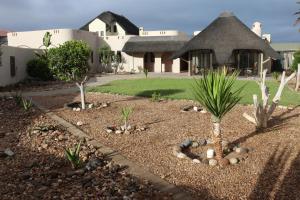 a garden in front of a house with a building at Amjicaja Guesthouse, Tours & Rentals in Walvis Bay