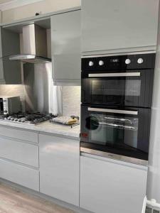 a kitchen with white cabinets and a black oven at Lovely 2 bed apartment with hot tub log burner and off street parking in Dumfries