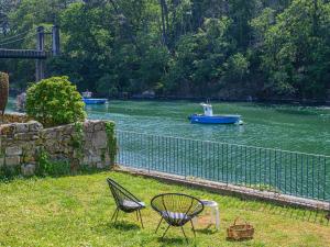 dos sillas y un bote azul en un río en Holiday Home Glann Aven by Interhome, en Le Bono