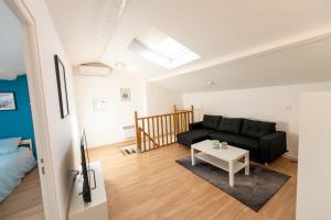 sala de estar con sofá negro y mesa en KASA DUPLEX - Climatisation - Balcon - Parking Privé, en Rive-de-Gier