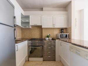 uma cozinha com armários brancos e um forno com placa de fogão em Apartment Michelangelo-2 by Interhome em Salou