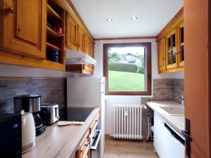 kuchnia z drewnianymi szafkami i oknem w obiekcie Apartment Le Nerey-2 by Interhome w mieście Saint-Gervais-les-Bains