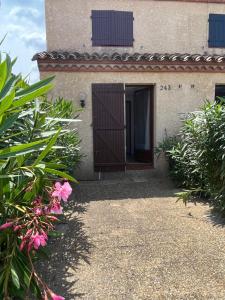 eine Haustür eines Hauses mit rosa Blumen in der Unterkunft Maison climatisé 2 chambres 700 m de la mer avec parking gratuit in Saint-Cyprien