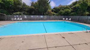 une grande piscine bleue avec des chaises et une clôture dans l'établissement 114 Sandbar, Private Pool, Short Walk to Beach, à Duck