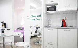 a kitchen with white cabinets and a table and a dining room at Apartment 4 You in Split in Split