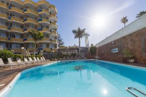 una gran piscina con sillas y un edificio en Hotel LIVVO Veril Playa, en Playa del Inglés
