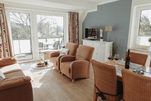 Una sala de estar con un sofá, una mesa y sillas. en Gästehaus Bröcker, en Büsum