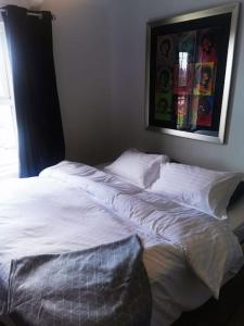 uma cama com lençóis brancos e almofadas num quarto em Newly Renovated 3 bedroom house em Taibach
