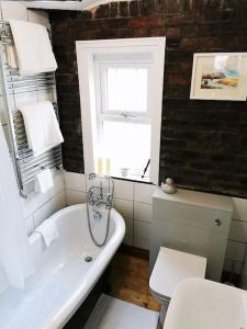 a bathroom with a white tub and a toilet at Newly Renovated 3 bedroom house in Taibach