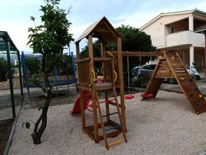 a playground with a wooden play structure next to a tree at Apartments Kairos - Bili 9 in Kaštela