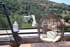 a hanging basket chair on a balcony with a view at VILLA LENA - ΑΝΔΡΟΣ in Batsi