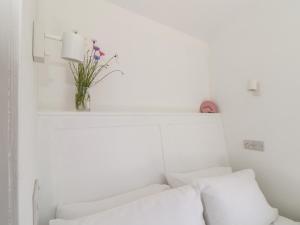 a white room with a white couch and a vase with flowers at Little Pip in Penzance