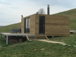 a small wooden cabin on a hill with a bench at Apartma Hisa konj in Pernica