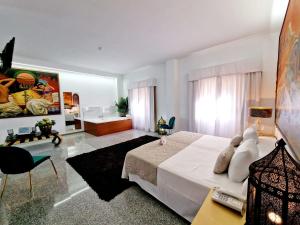 Hotel Plaza Del Castillo في مالقة: غرفة نوم بسرير ابيض وغرفة معيشة