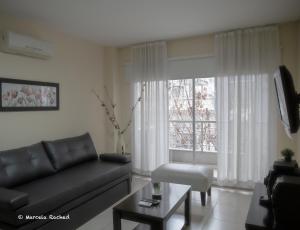 sala de estar con sofá negro y ventana en Arenales Suites en Buenos Aires