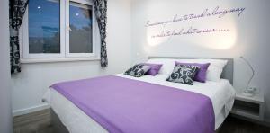 a bedroom with a bed with purple sheets and pillows at Apartment 4 You in Split in Split