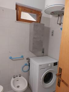 a small bathroom with a washing machine and a toilet at La mia Casa a Talamone in Talamone