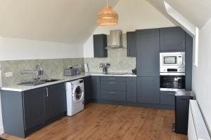 a kitchen with gray cabinets and a washer and dryer at Hillside House in Elgol