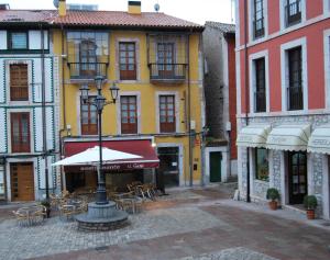 リャネスにあるApartamentos Plaza Mayorの黄色い建物の前のテーブルと椅子のある通り