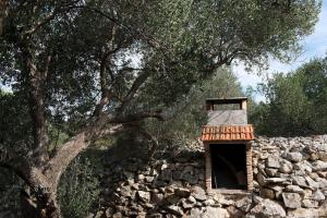 a stone wall with a window and a tree at House Petra in Sali